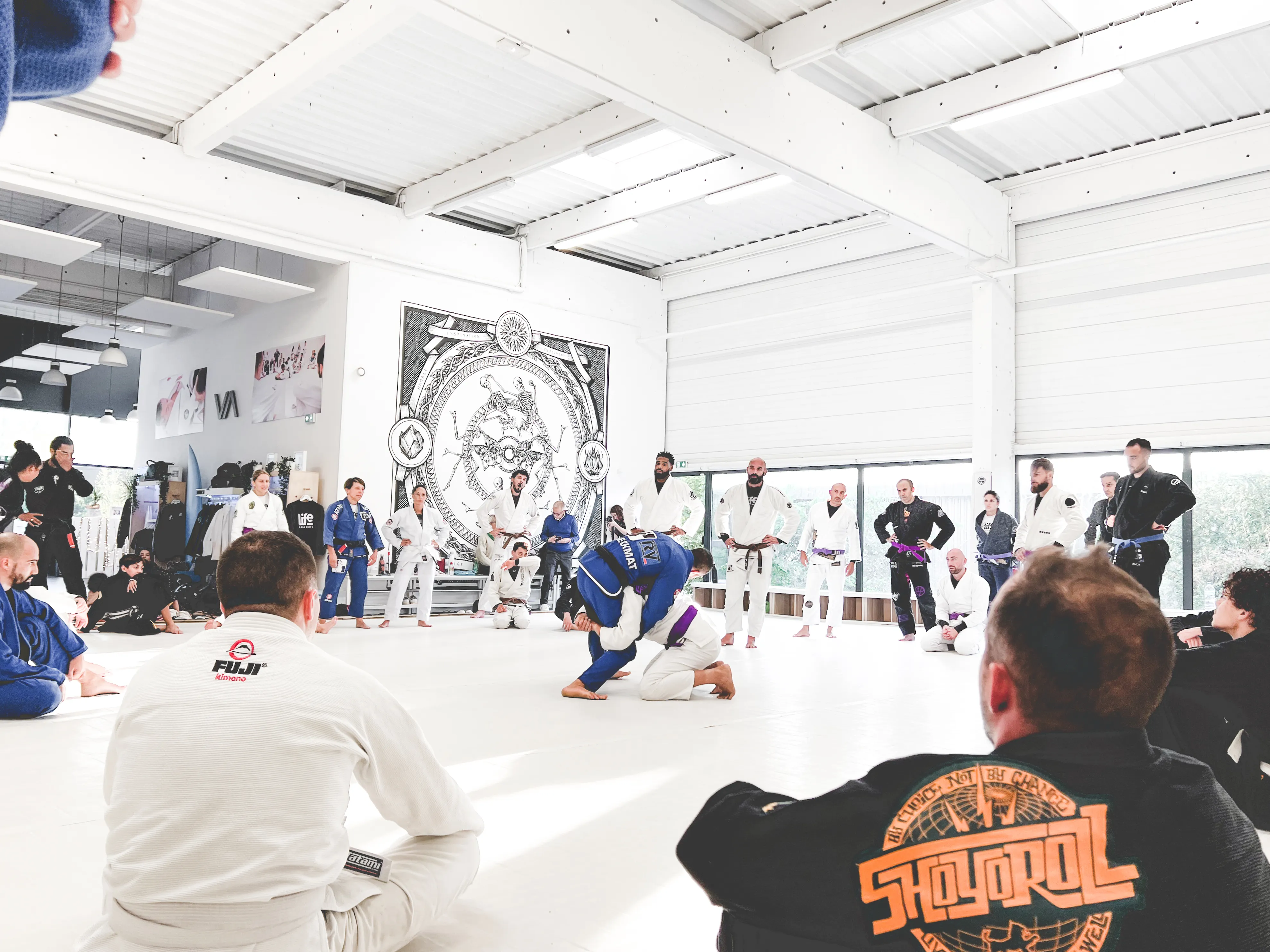 Séminaire à Life Academy : les pratiquants assis en cercle sur le grand tatami blanc