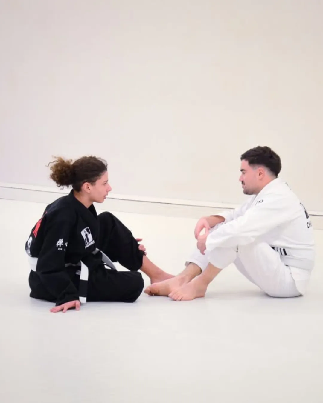 Deux pratiquants assis face à face sur le tatami, en pleine explication
